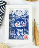 Linogravure bleue d’un chien Akita assis dans un champ, vu de trois quarts, avec des montagnes japonaises et des libellules en arrière-plan