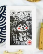 Linogravure en noir et blanc d’un chien Akita assis dans un champ, vu de trois quarts, avec des montagnes japonaises et des libellules en arrière-plan