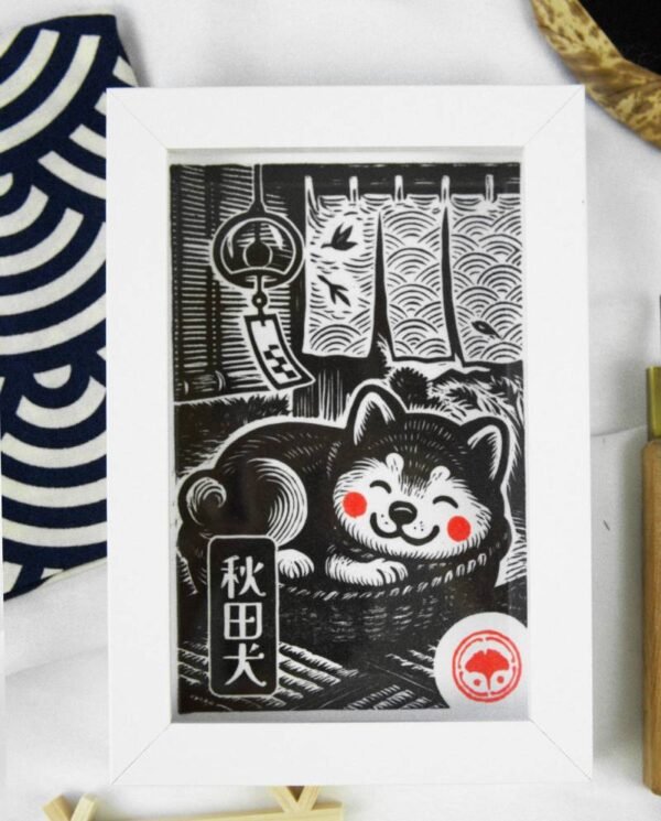 Linogravure noire d’un chien Akita endormi dans un panier sur un tatami, avec un noren et un furin en arrière-plan