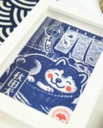 Linogravure bleue d’un chien Akita endormi dans un panier sur un tatami, avec un noren flottant et un furin suspendu en arrière-plan