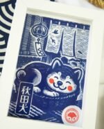 Linogravure bleue d’un chien Akita endormi dans un panier sur un tatami, avec un noren flottant et un furin suspendu en arrière-plan