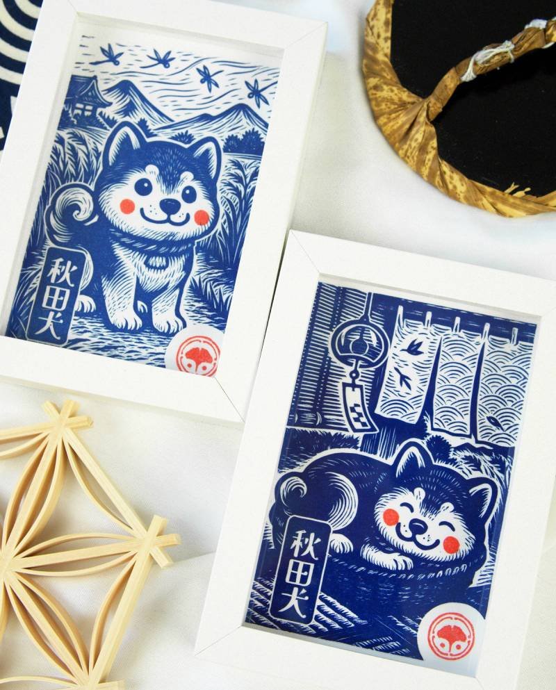 Linogravure bleue d’un chien Akita endormi dans un panier sur un tatami, avec un noren flottant et un furin suspendu en arrière-plan