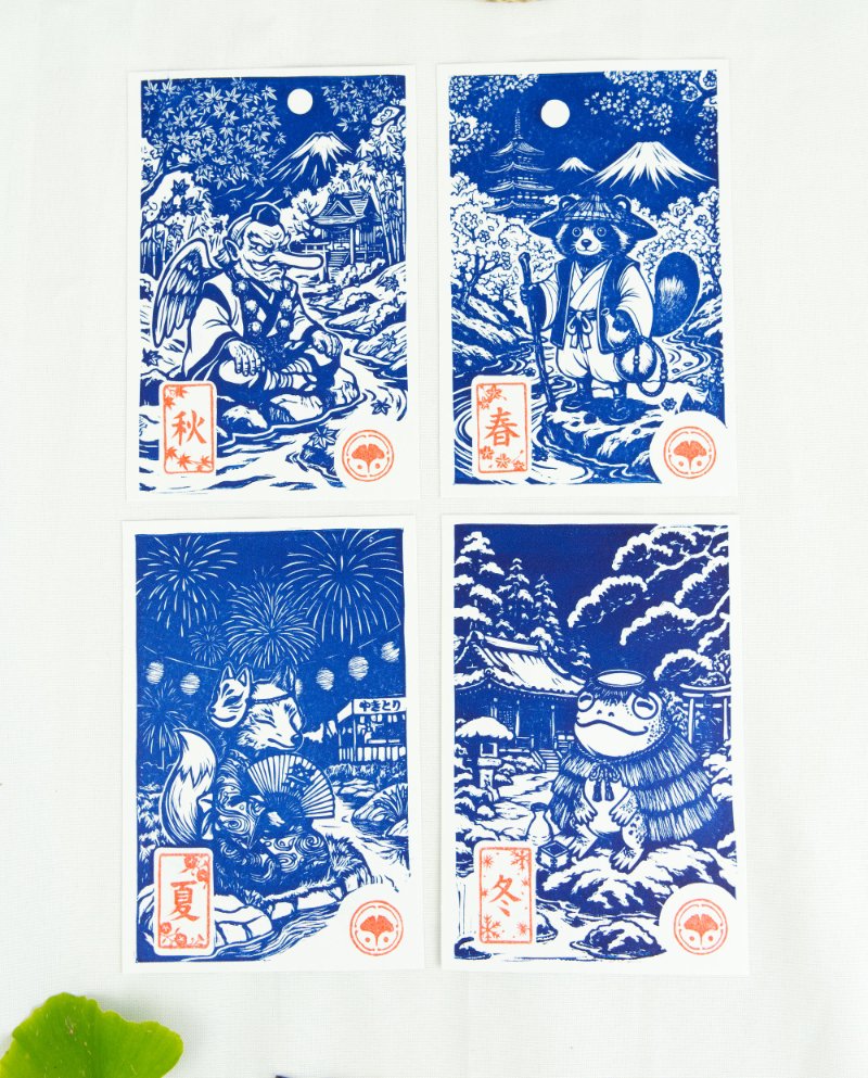 Estampes japonaises Yokai des saisons au format A6 : linogravures artisanales représentant un kappa, un tengu, un kitsune et un tanuki, imprimées à la main en noir, bleu et violet.