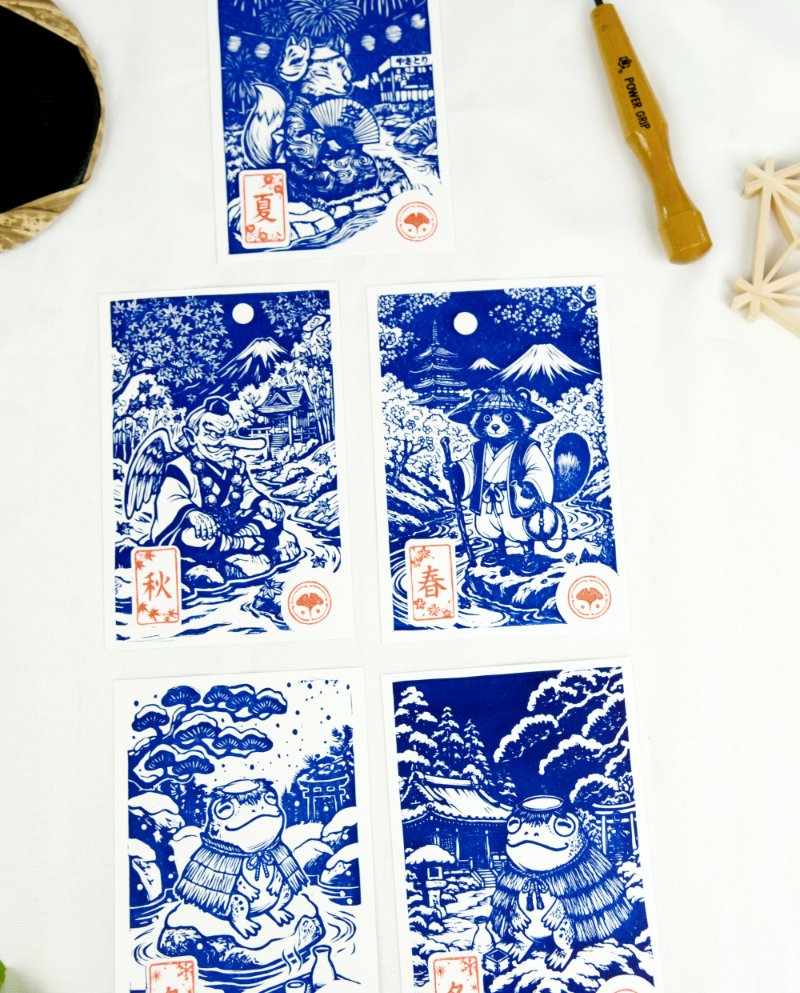 Estampes japonaises Yokai des saisons au format A6 : linogravures artisanales représentant un kappa, un tengu, un kitsune et un tanuki, imprimées à la main en noir, bleu et violet.