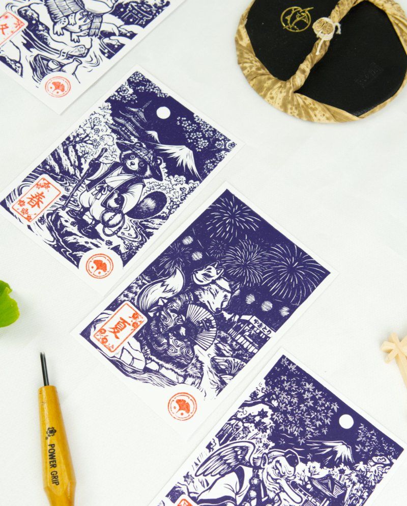 Estampes japonaises Yokai des saisons au format A6 : linogravures artisanales représentant un kappa, un tengu, un kitsune et un tanuki, imprimées à la main en noir, bleu et violet.