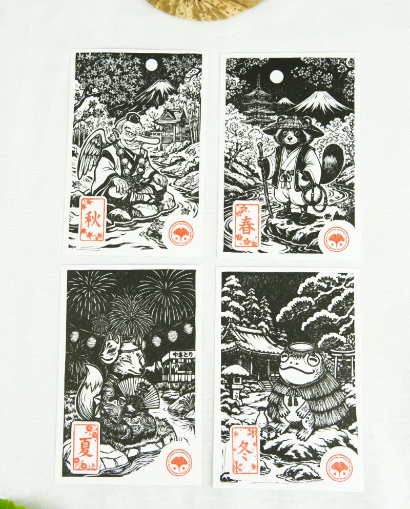 Estampes japonaises Yokai des saisons au format A6 : linogravures artisanales représentant un kappa, un tengu, un kitsune et un tanuki, imprimées à la main en noir, bleu et violet.