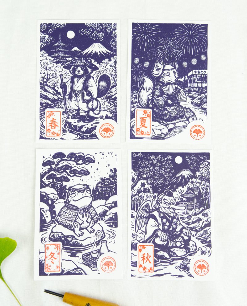 Estampes japonaises Yokai des saisons au format A6 : linogravures artisanales représentant un kappa, un tengu, un kitsune et un tanuki, imprimées à la main en noir, bleu et violet.